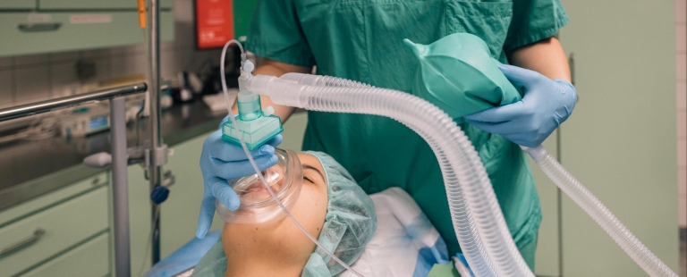 Profissional de enfermagem a ajustar equipamento de ventilação não invasiva em ambiente hospitalar.